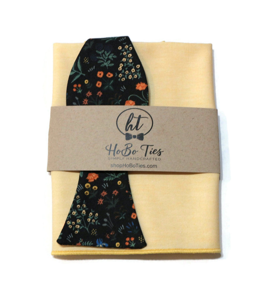 Black Menagerie Garden Floral Bow Tie with matching pocket square on yellow fabric.