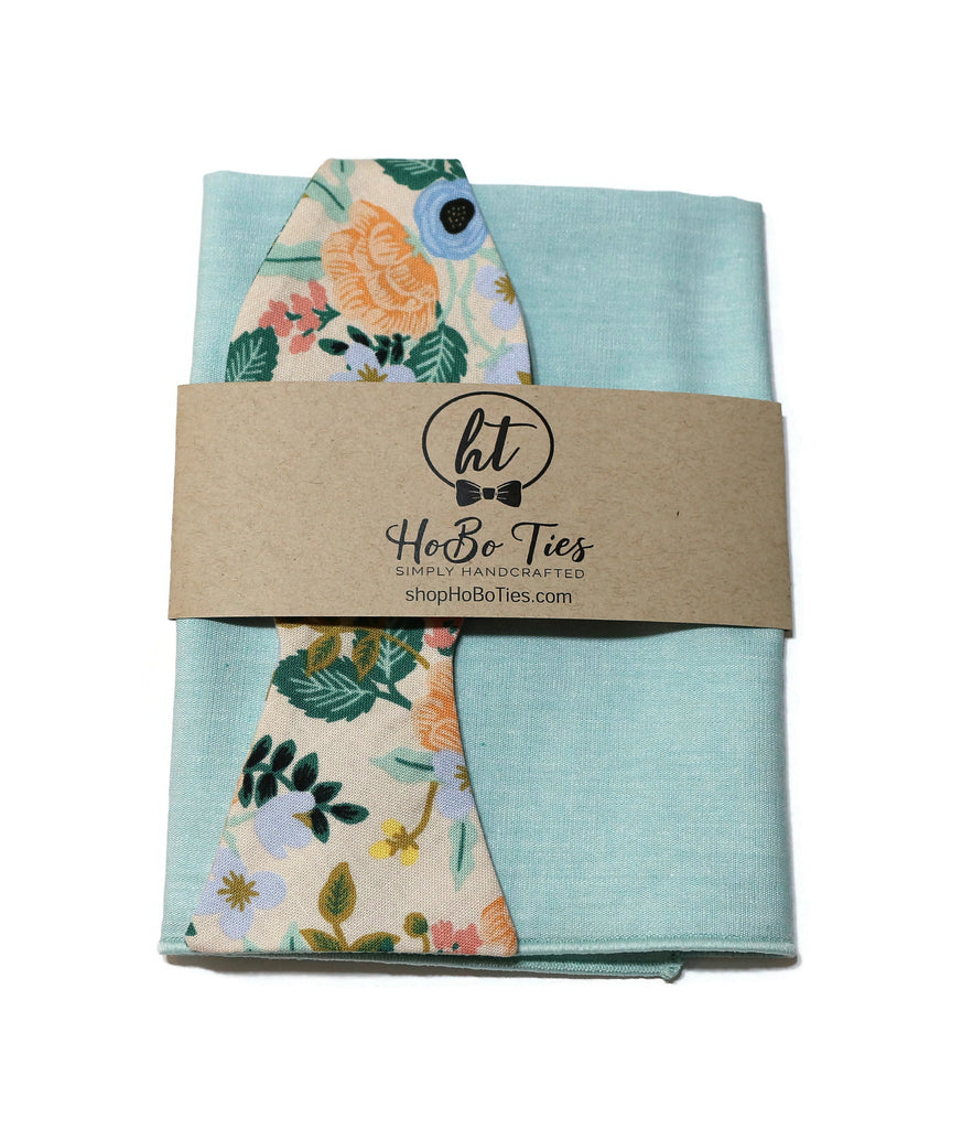 Blush Birch Floral Bow Tie with floral tag on a mint green background, showcasing handcrafted neckties and handmade bow ties.