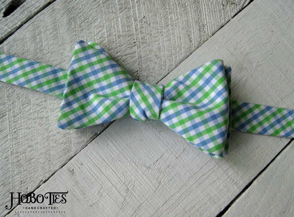 Cornflower & Lime Tattersall Bow Tie on a wooden surface, handcrafted for men’s formal wear accessories.