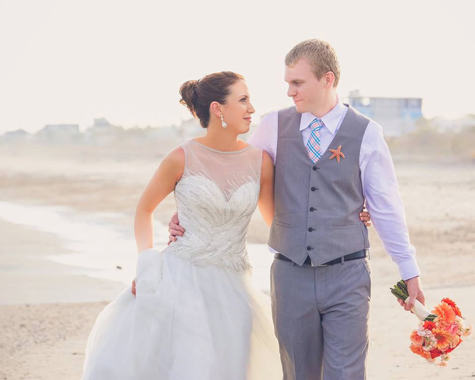 Couple walking on the beach in wedding attire, showcasing romantic wedding vibes and beach elegance.